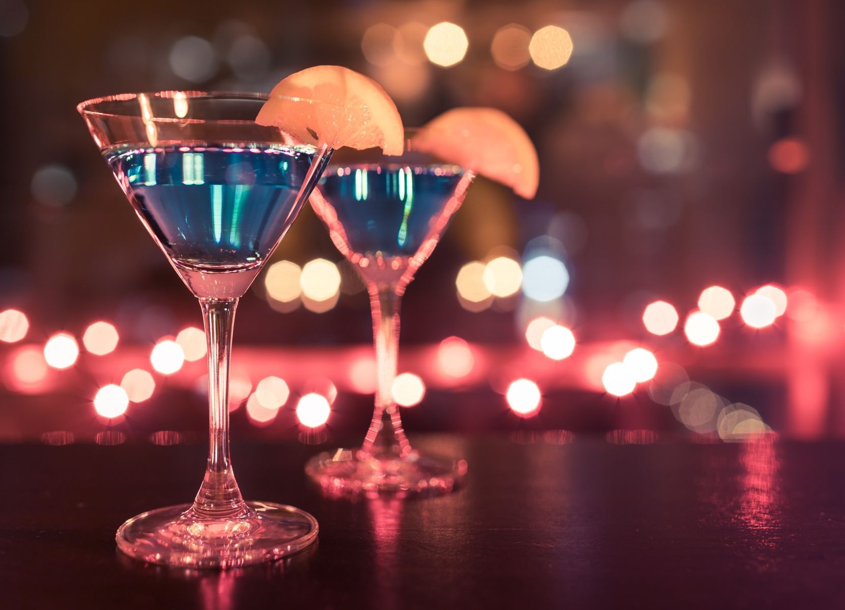 Een blauw drankje op een tafel met sfeerlicht op de achtergrond. Het is namelijk feest want Prosos is 7 jaar.
